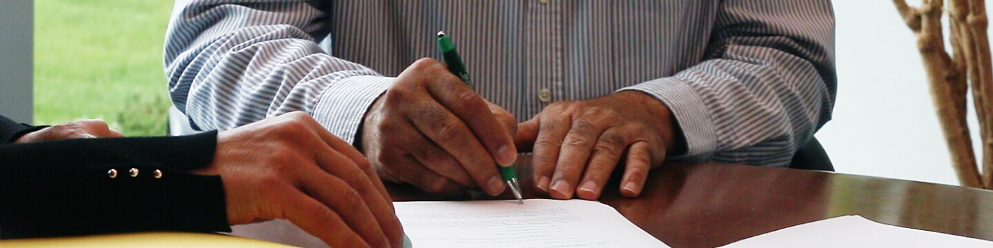 A man signing a contract at table